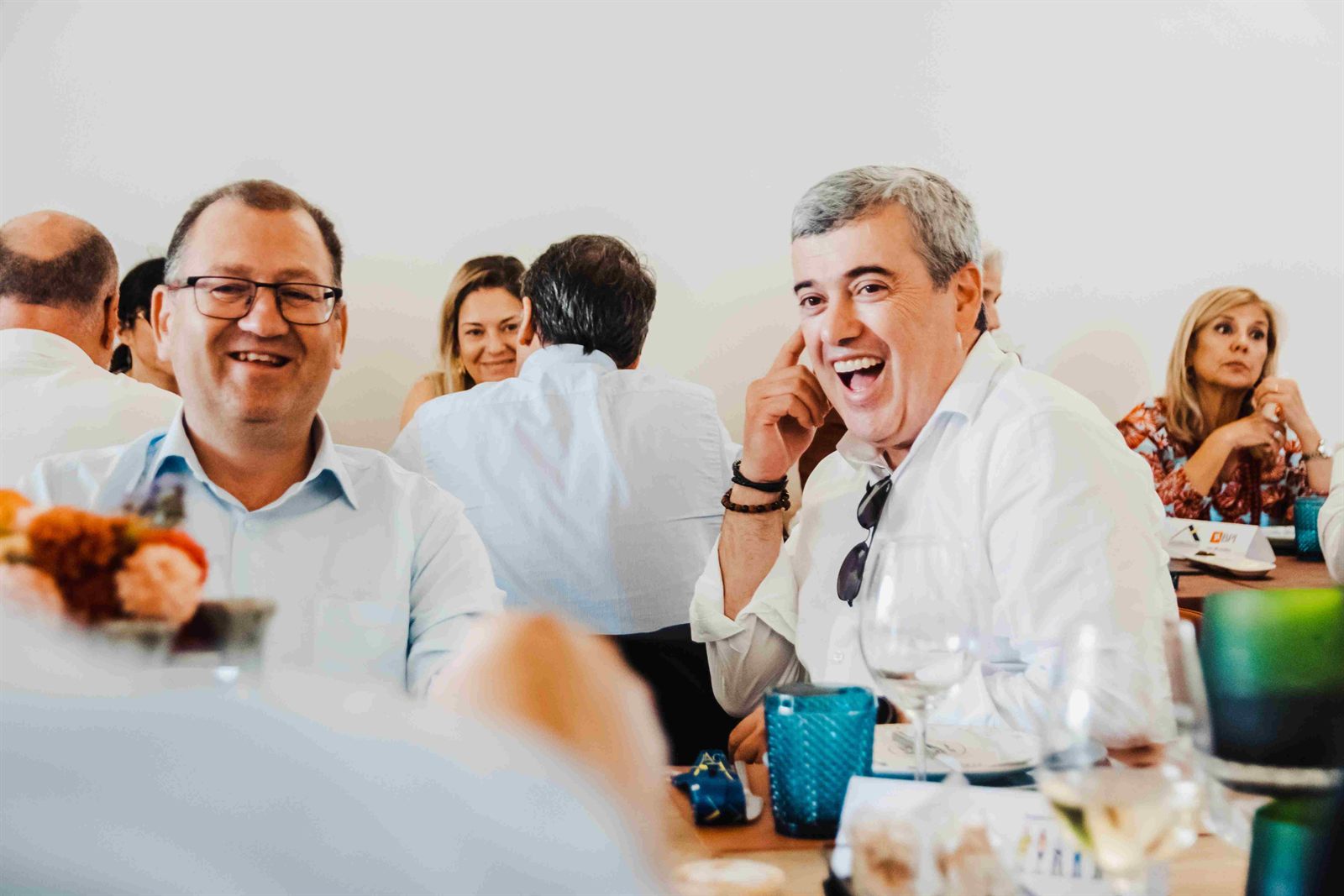 Convidados a rir à mesa durante o almoço do 25º aniversário da agência.