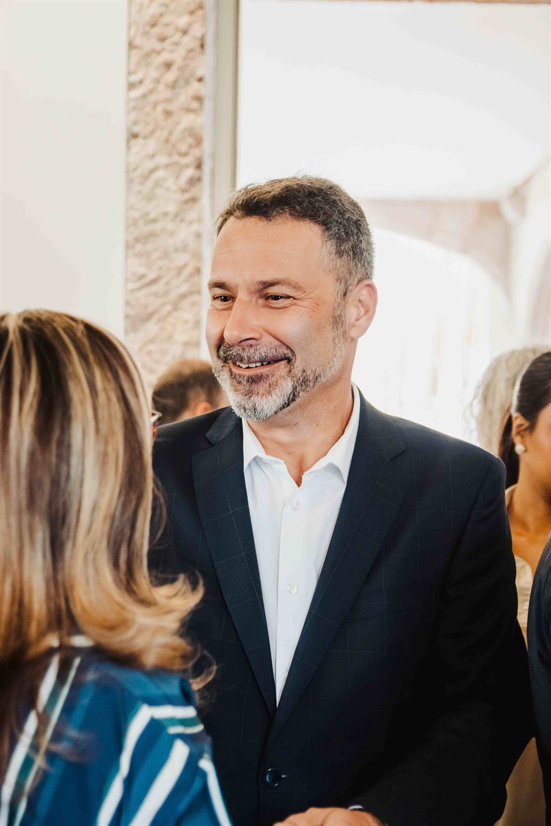 Convidado sorri durante a receção do 25º aniversário da agência.